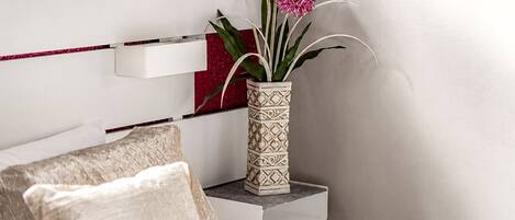 A white bedside table with a decorative vase containing pink flowers.