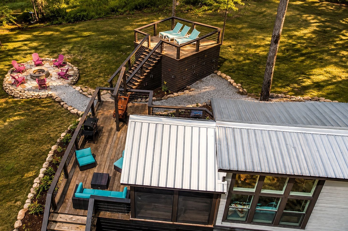 A deck with outdoor seating and a fire pit, surrounded by a stone fire ring.