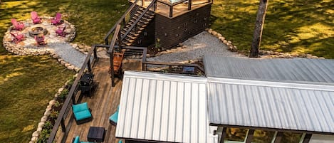 A deck with outdoor seating and a fire pit, surrounded by a stone fire ring.