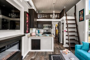 A modern kitchen with a central island, a staircase, and a blue sofa.