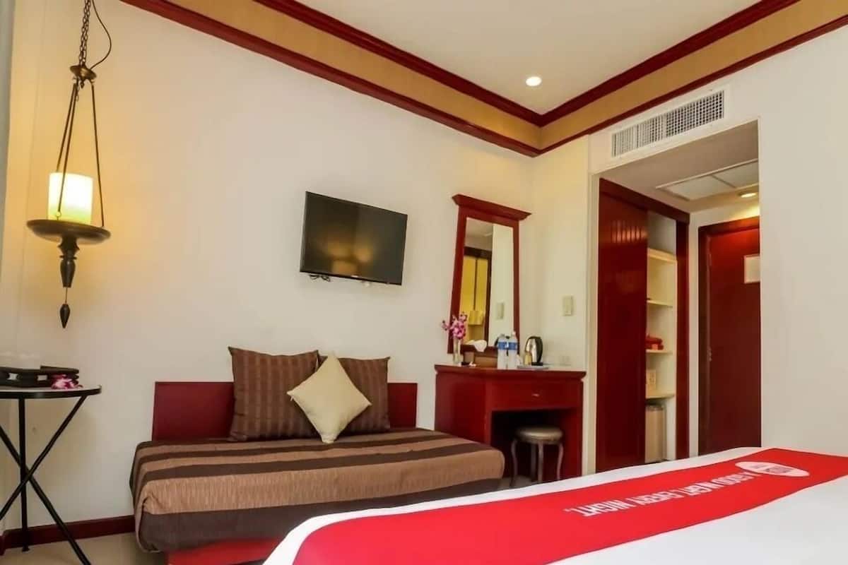 Une chambre d’hôtel équipée d’un lit, d’un bureau, d’une chaise, d’une télévision, d’un miroir et d’une armoire.
