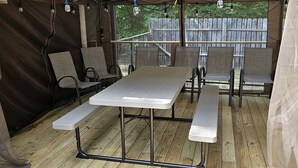 A covered outdoor dining area with a table and benches, surrounded by a tent-like structure. - Gorgeous Cottage with Stunning Sights in Wellston, Michigan (Wellston)