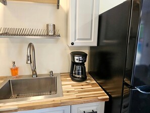 A kitchen with a stainless steel sink, a coffee maker, and a black refrigerator. - Gorgeous Cottage with Stunning Sights in Wellston, Michigan (Wellston)