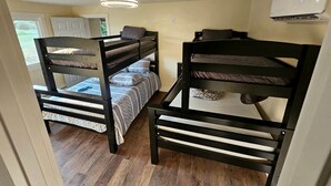A room with bunk beds, a ceiling fan, and an air conditioning unit. - Gorgeous Cottage with Stunning Sights in Wellston, Michigan (Wellston)