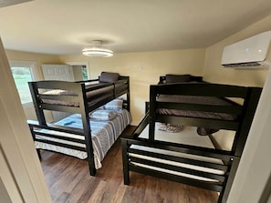 A room with bunk beds, a ceiling fan, and an air conditioning unit.