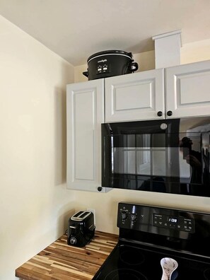 A kitchen with white cabinets, a black microwave, a toaster, and a stove.