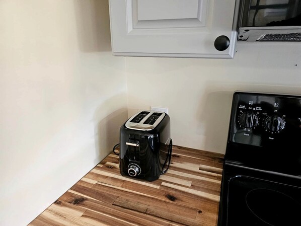A kitchen with a toaster on a wooden countertop, a stove, and a white door.