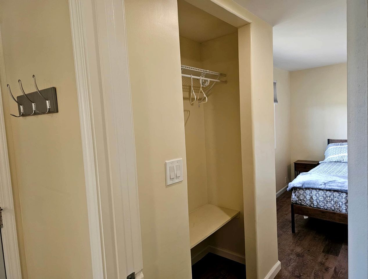 A bedroom with a bed, a closet with hanging space, and a small bedside table.