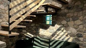 A stone-walled interior with a wooden staircase leading to a loft area.