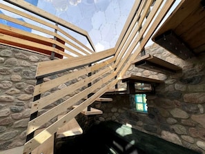 A wooden staircase with stone walls and a window.