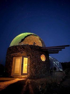 A dome-shaped building with a stone exterior and a large glass dome on top.
