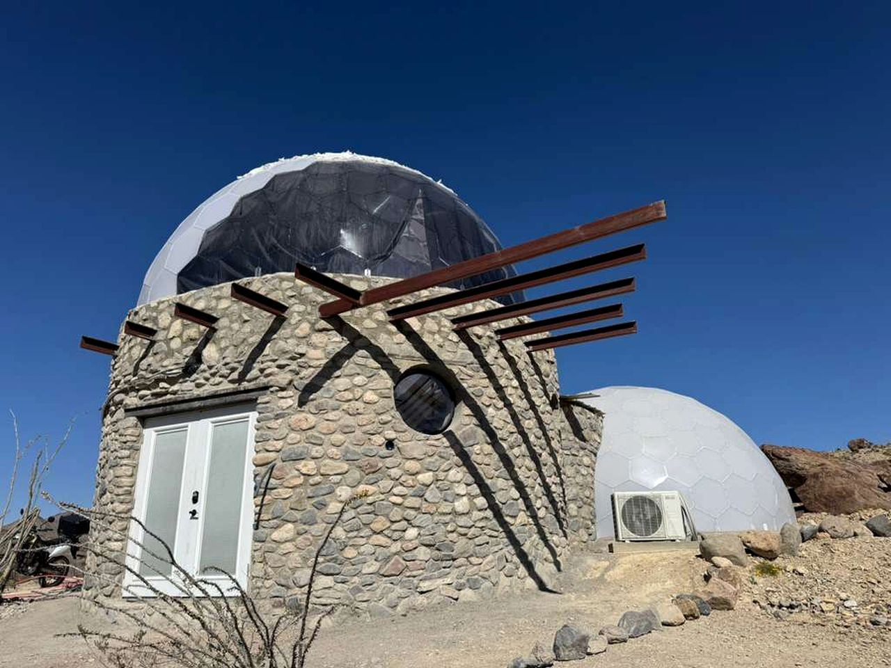 A stone building with a dome structure, a door, and a window.