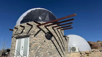 A stone building with a dome structure, a door, and a window.