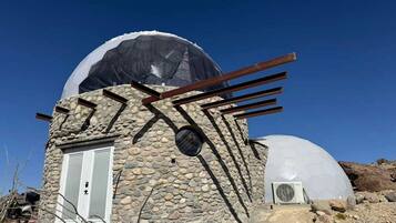 A stone building with a dome structure, a door, and a window.