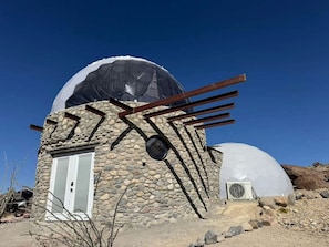 A stone building with a dome structure, a door, and a window.