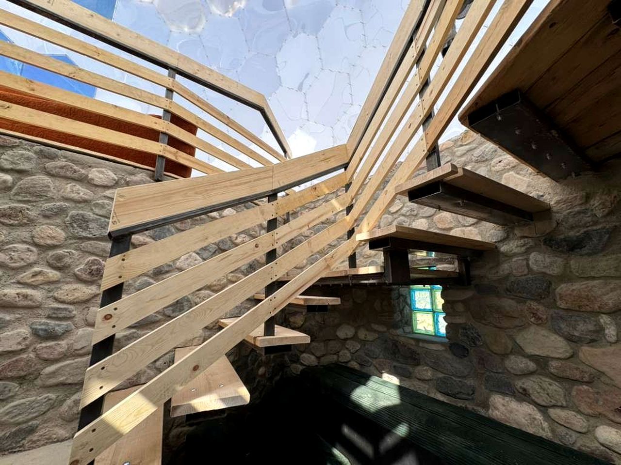 A wooden staircase with stone walls and a window.