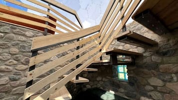 A wooden staircase with stone walls and a window.