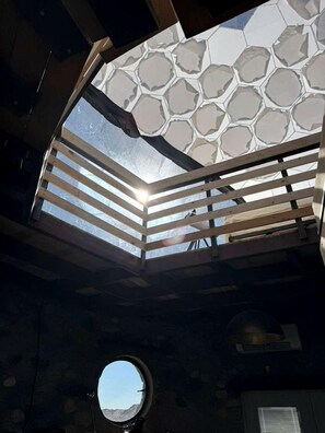 Una habitación con tragaluz, ventanal circular y vistas al cielo.