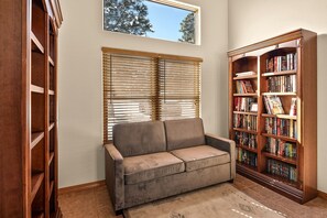 A room with a sofa, a bookshelf, and a window with blinds. - Cozy and Pet Friendly Cottage a Moment's Drive from the Grand Canyon National Park, Arizona (Williams)