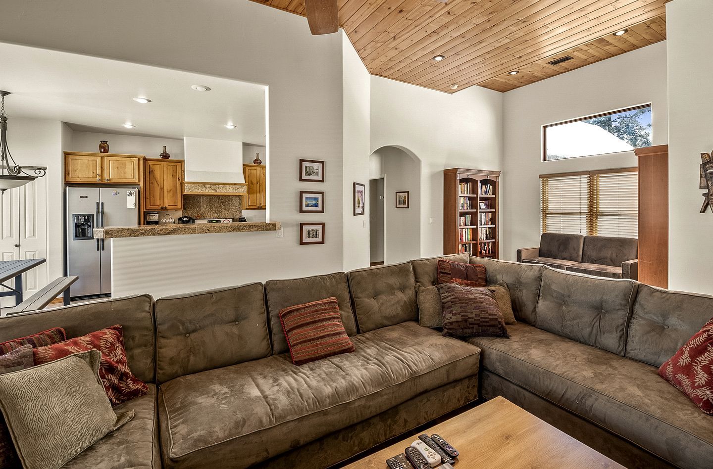 A modern living room with a sectional sofa, a wooden coffee table, and a kitchen in the background.