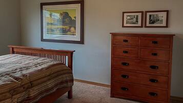 Un dormitorio con una cama, un aparador y dos cuadros en la pared.