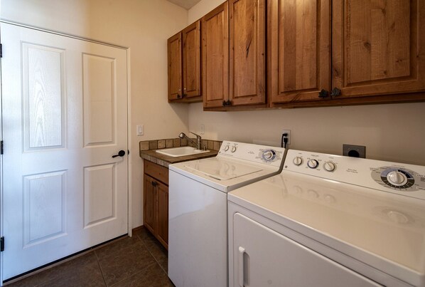A laundry room with a washing machine, dryer, and sink. - Cozy and Pet Friendly Cottage a Moment's Drive from the Grand Canyon National Park, Arizona (Williams)