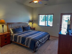 A bedroom with a bed, two bedside tables, a nightstand, a ceiling fan, and a window with blinds. - Cozy and Pet Friendly Cottage a Moment's Drive from the Grand Canyon National Park, Arizona (Williams)