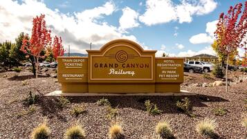 Señal del Gran Cañón Railway con indicaciones hacia el depósito de trenes, venta de boletos, restaurante, registro de hotel, parque para vehículos recreativos y centro para mascotas.