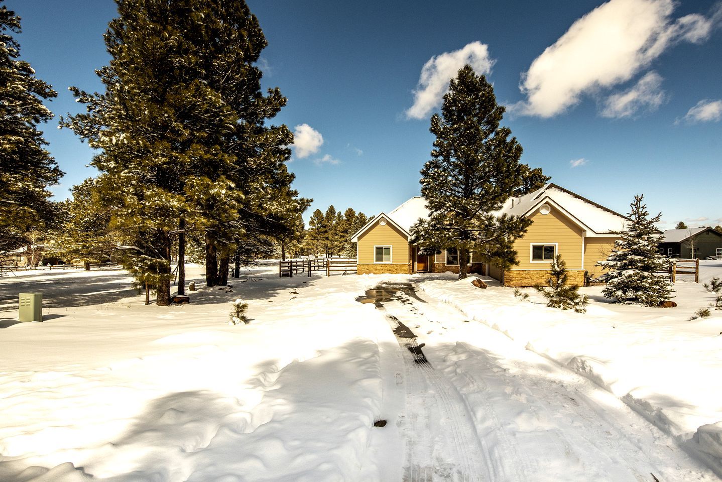 A snow-covered landscape with a building featuring a gabled roof and a stone foundation.