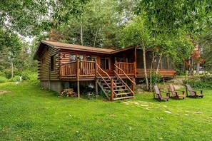 A log cabin with a deck, outdoor seating, and a grill. - Pet-Friendly Log Cabin Retreat in Ely for Magical Minnesota Family Vacations (Ely)