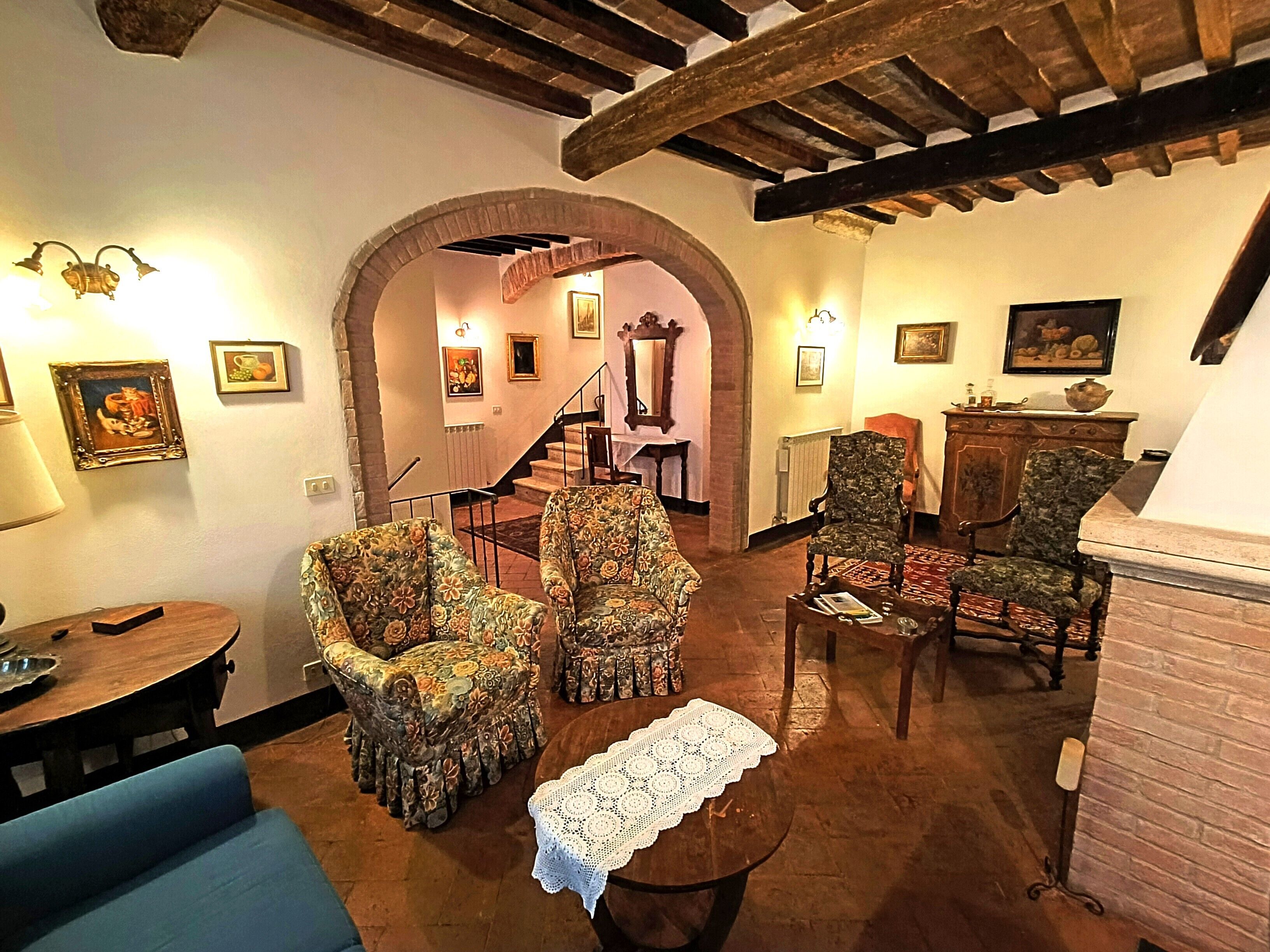 Ein gemütliches Wohnzimmer mit floralen Sesseln, einem kleinen Couchtisch und einer Treppe, die zu einer oberen Etage führt.