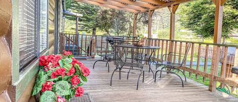 Eine überdachte Terrasse im Freien mit Holzboden, Metallstühlen und einem Tisch.