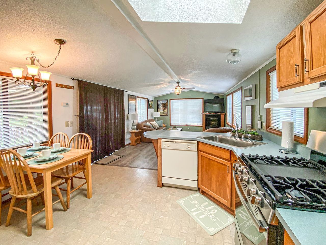 A kitchen with a dining area, wooden cabinets, a stove, and a ceiling fan.