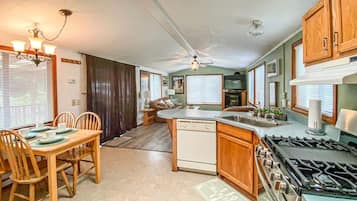 A kitchen with a dining area, wooden cabinets, a stove, and a ceiling fan.