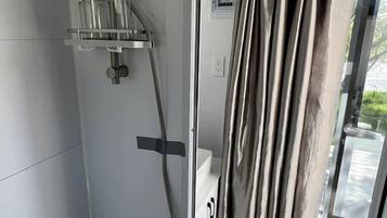 Um chuveiro moderno com box de vidro, chuveiro manual e torneira embutida na parede.