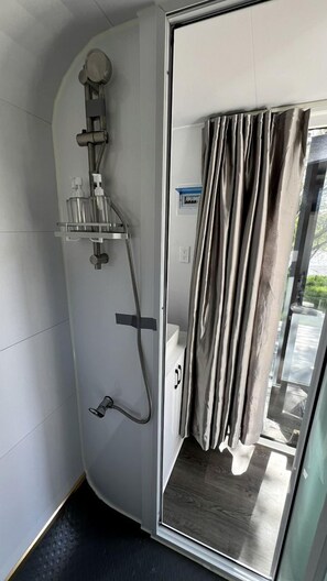 A modern shower with a glass enclosure, a handheld showerhead, and a wall-mounted faucet.