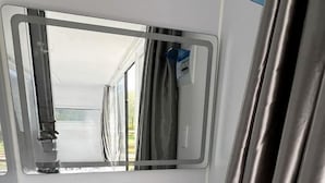 Un bagno con lavandino bianco, uno specchio e una tenda della doccia.