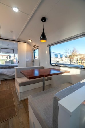 Ein kompaktes Wohnmobil-Interieur mit Bett, Sitzgelegenheit und Fenster mit Aussicht.