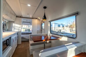Ein kompaktes Wohnmobil-Interieur mit Küchenzeile, Essbereich mit Tisch und Bank sowie Fenster mit Aussicht.