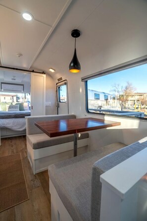 Ein kompaktes Wohnmobil-Interieur mit Bett, Sitzgelegenheit und Fenster mit Aussicht.