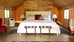 A tent-style room with a bed, two chairs, a radiator, and a lamp. - Gorgeous Tent Rental for Vermont Getaways in Nature (Springfield)
