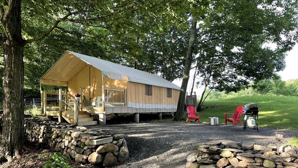 A rustic cabin with a porch, stone walls, and a gravel driveway. - Gorgeous Tent Rental for Vermont Getaways in Nature (Springfield)