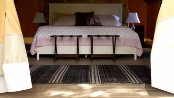 A cozy bedroom with a bed, bedside tables, a bedside lamp, a rug, and a welcome mat.