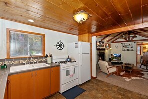 A kitchen with wooden cabinets, a stove, and a refrigerator. - Forest Cottage with Outdoor Jacuzzi and Picnic Space in California (Big Bear Lake)