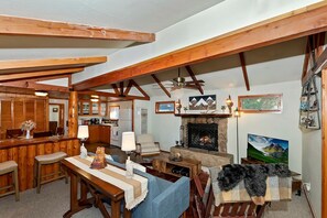 Ein gemütliches Wohnzimmer mit Kamin, Holzbalken, Essbereich und Küche.