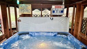 Ein Whirlpool mit Holzkonstruktion, Warnschildern und Blick ins Freie.