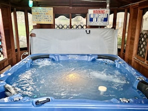 A hot tub with a wooden structure, warning signs, and a view of the outdoors.