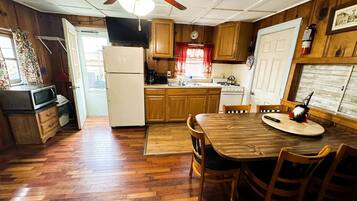 A wooden-paneled kitchen with a dining table, chairs, and a ceiling fan.