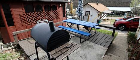 A barbecue grill, picnic table, and outdoor seating area with a wooden deck.