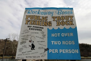 Letrero del muelle de pesca de truchas Rockaway Beach, con una lista de permisos de pesca y la regla de no usar más de dos cañas por persona.